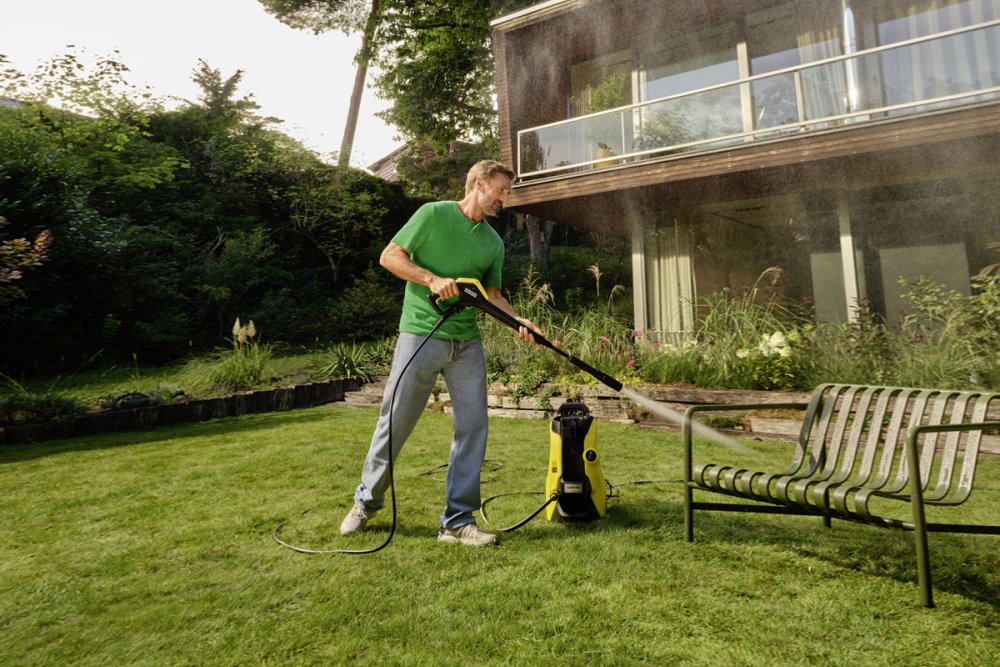 Person reinigt Gartenmöbel mit Hochdruckreiniger
